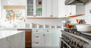 Bright kitchen with white cabinets, hexagon tile and a marble island
