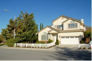 Two-story home with a white picket fence and a closed garage door