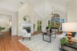 Bright living room with a vaulted ceiling, fireplace and large arched window