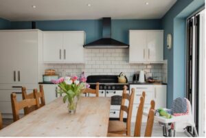 Kitchen with white cabinets, a wooden dining table and a vase of tulips