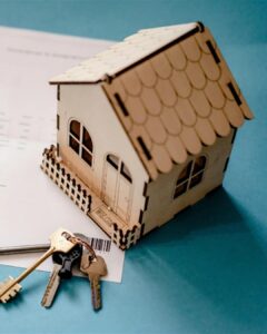 Small wooden model house and keys resting on a closing document, representing a home seller's net proceeds