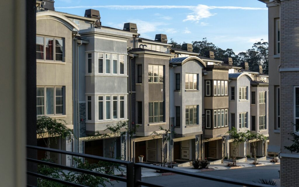 Row of gray stucco townhomes with garages and bay windows