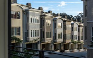 Row of gray stucco townhomes with garages and bay windows