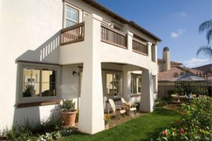 Two-story white stucco home with a balcony and a landscaped yard