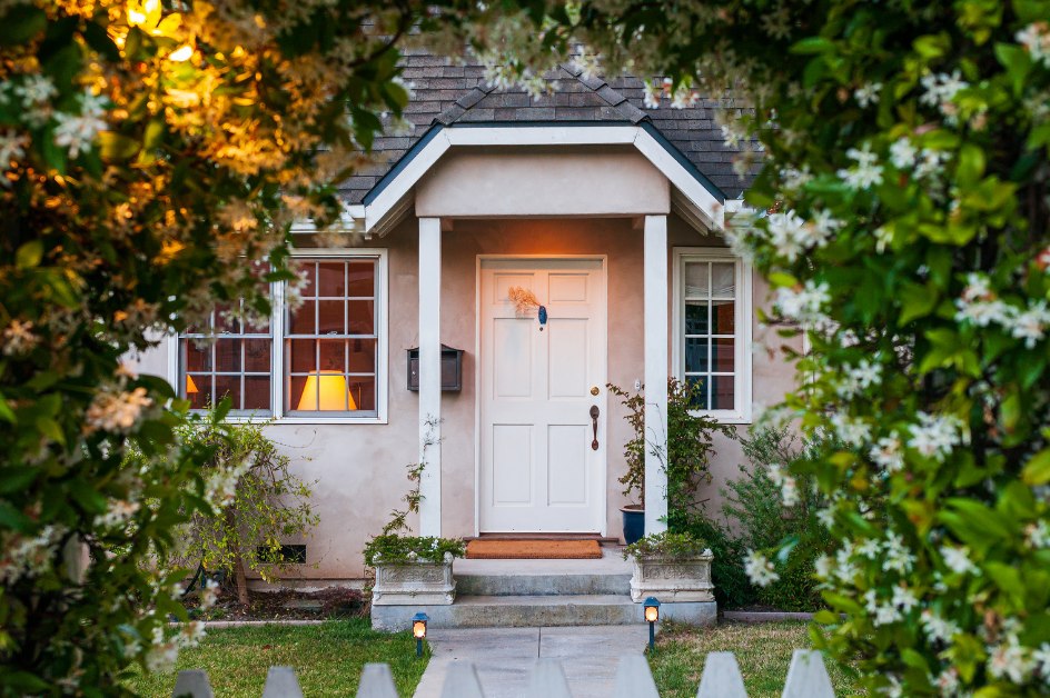 Cottage-style home with a white front door framed by flowering vines