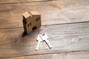 A small wooden house model and house keys on a wood table