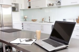 Laptop and notebook on a counter in a white kitchen