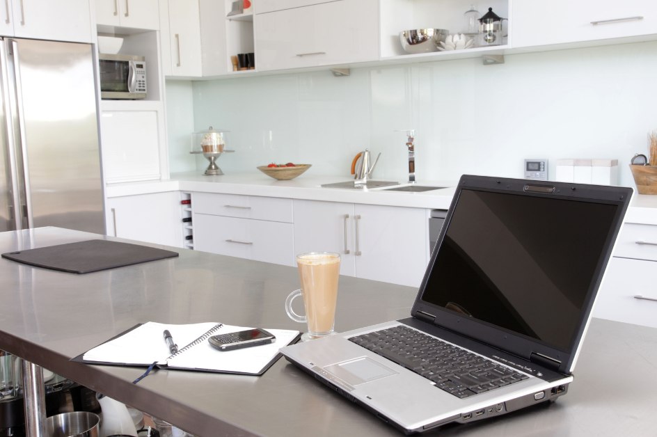 Laptop and notebook on a counter in a white kitchen